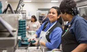 Morrison Healthcare associates happily preparing meals in a commercial kitchen